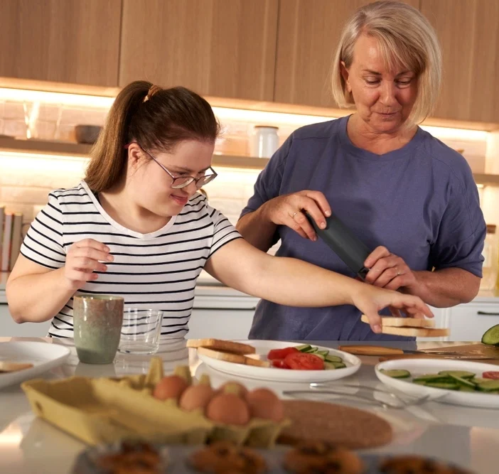 Disabled woman preparing sandwich with carer
