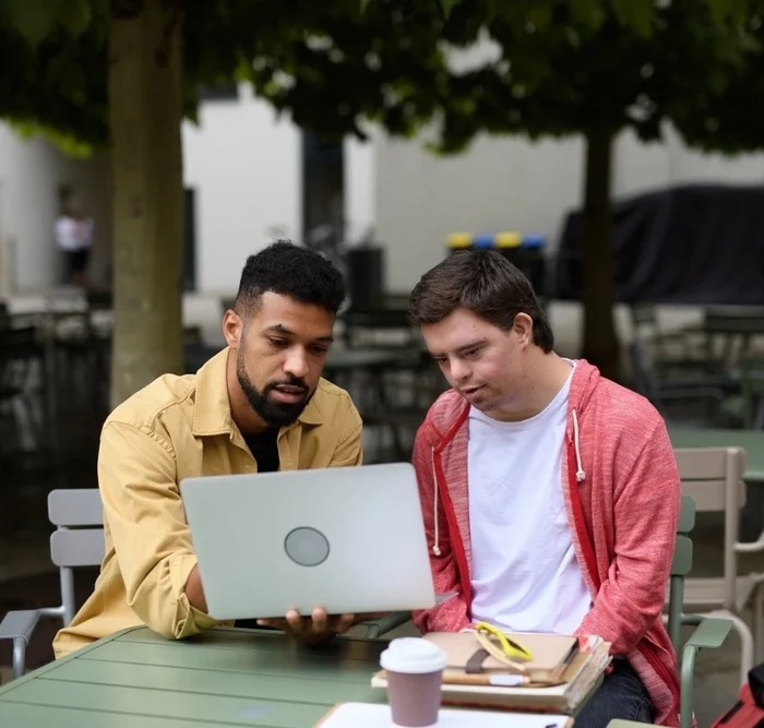 Support worker and disabled man looking at laptop